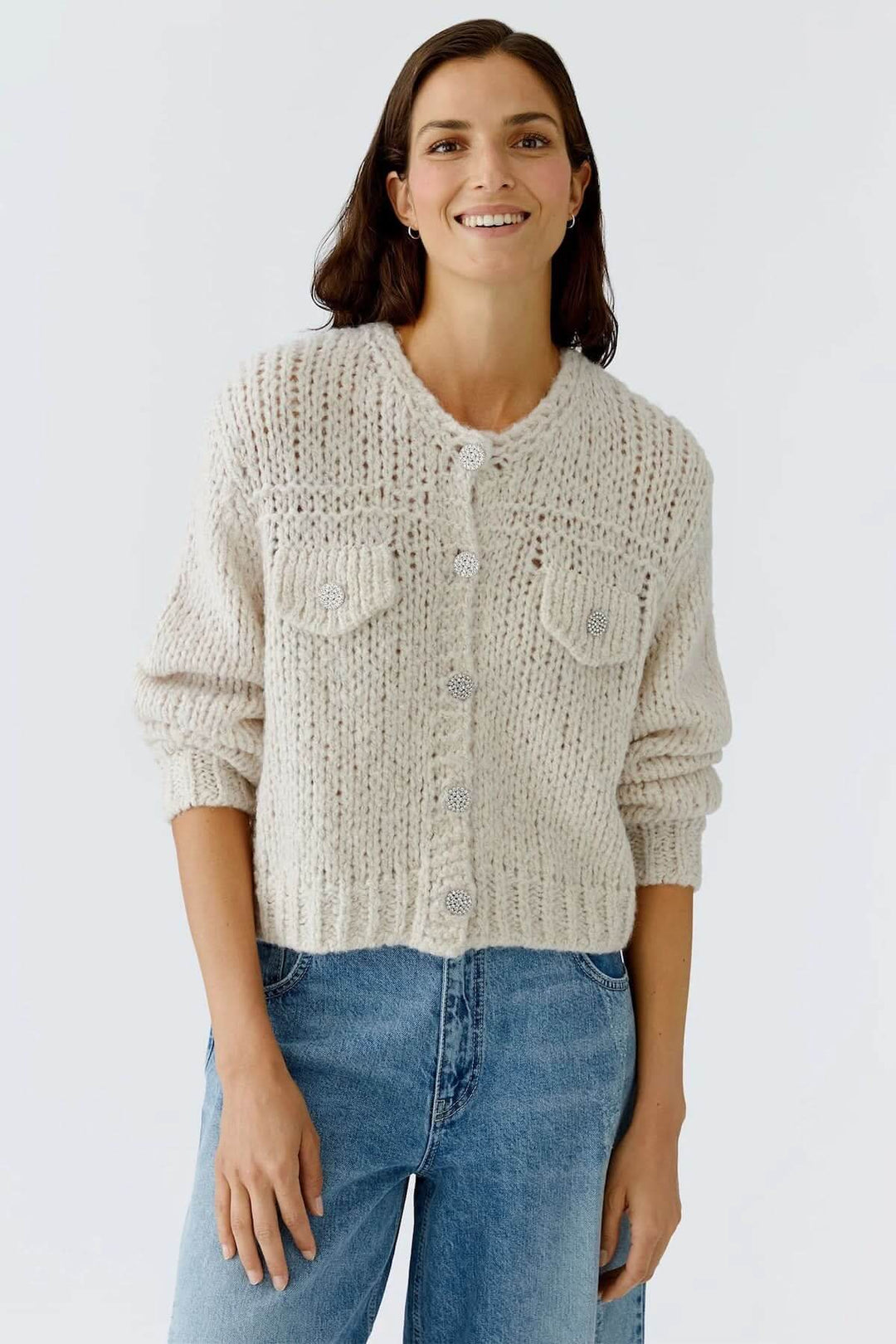 Veste en tricot épais à boutons bijoux porté par mannequin, maille ajourée, style chic et cosy pour l'automne et l'hiver.