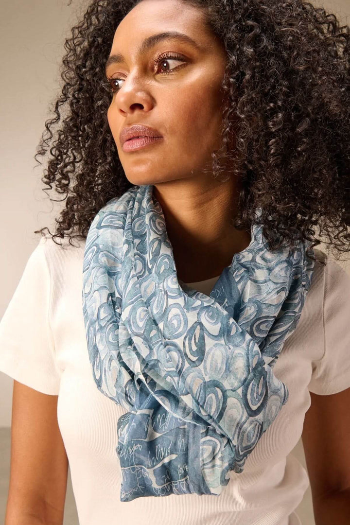 Femme portant un foulard léger à imprimé bleu, accessoire polyvalent et élégant pour un style décontracté ou habillé.