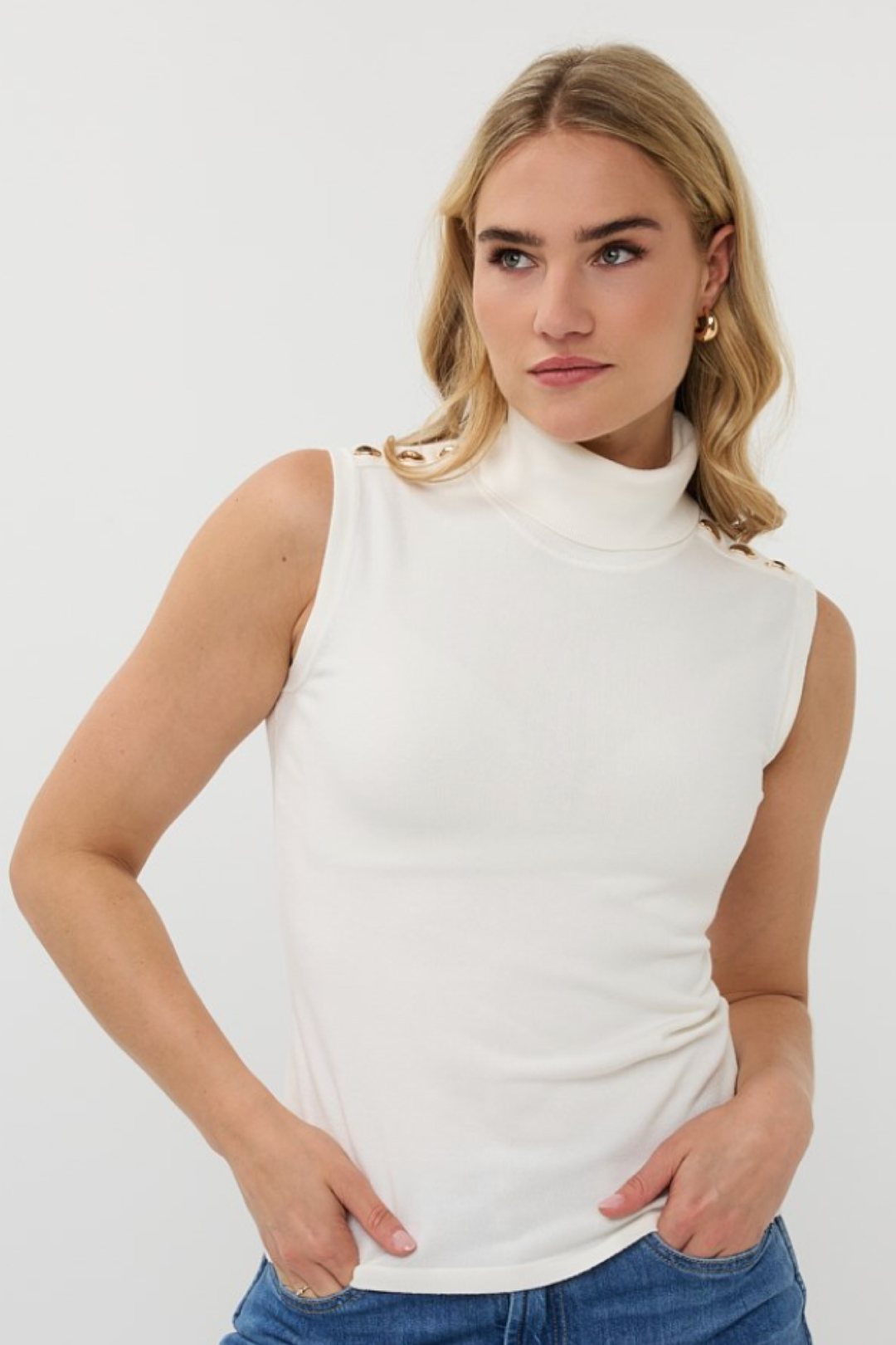 Col roulé sans manches blanc avec boutons métalliques aux épaules, idéal pour un look élégant au quotidien.