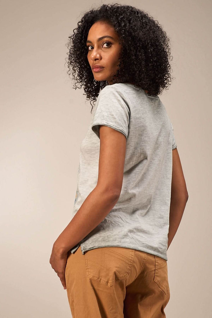 Femme portant un t-shirt à manches courtes gris, vue de dos, avec des cheveux crépus et une coupe moderne.