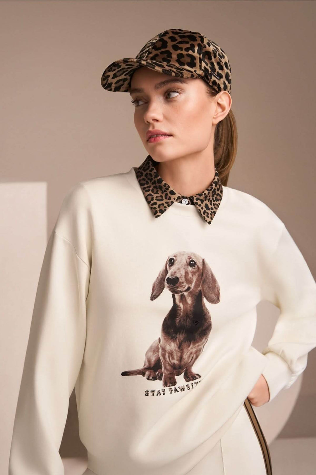 Femme portant coton ouaté imprimé chien "Stay Pawsitive", look décontracté avec casquette et col imprimé animal.