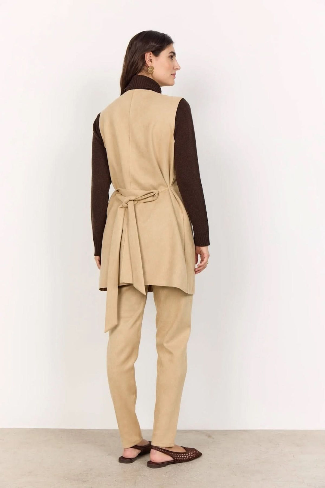 Gilet sans manches beige, porté avec un haut marron et pantalon assorti, vue de dos.
