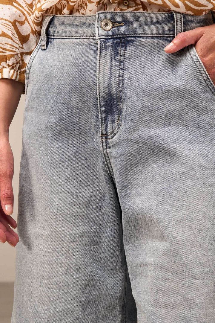 Bermuda ample en denim délavé, coupe confortable, longueur genou, avec revers élégants, idéal pour un look casual chic.