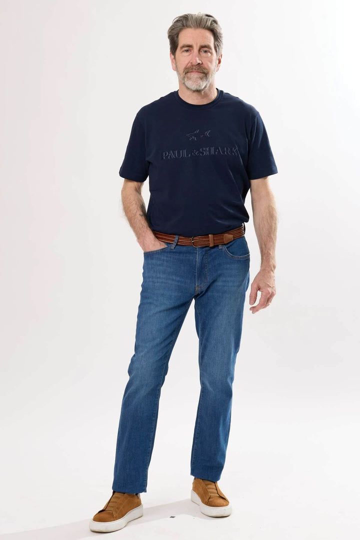 Homme portant un t-shirt bleu marine et un jean classique à la coupe droite avec des chaussures décontractées.