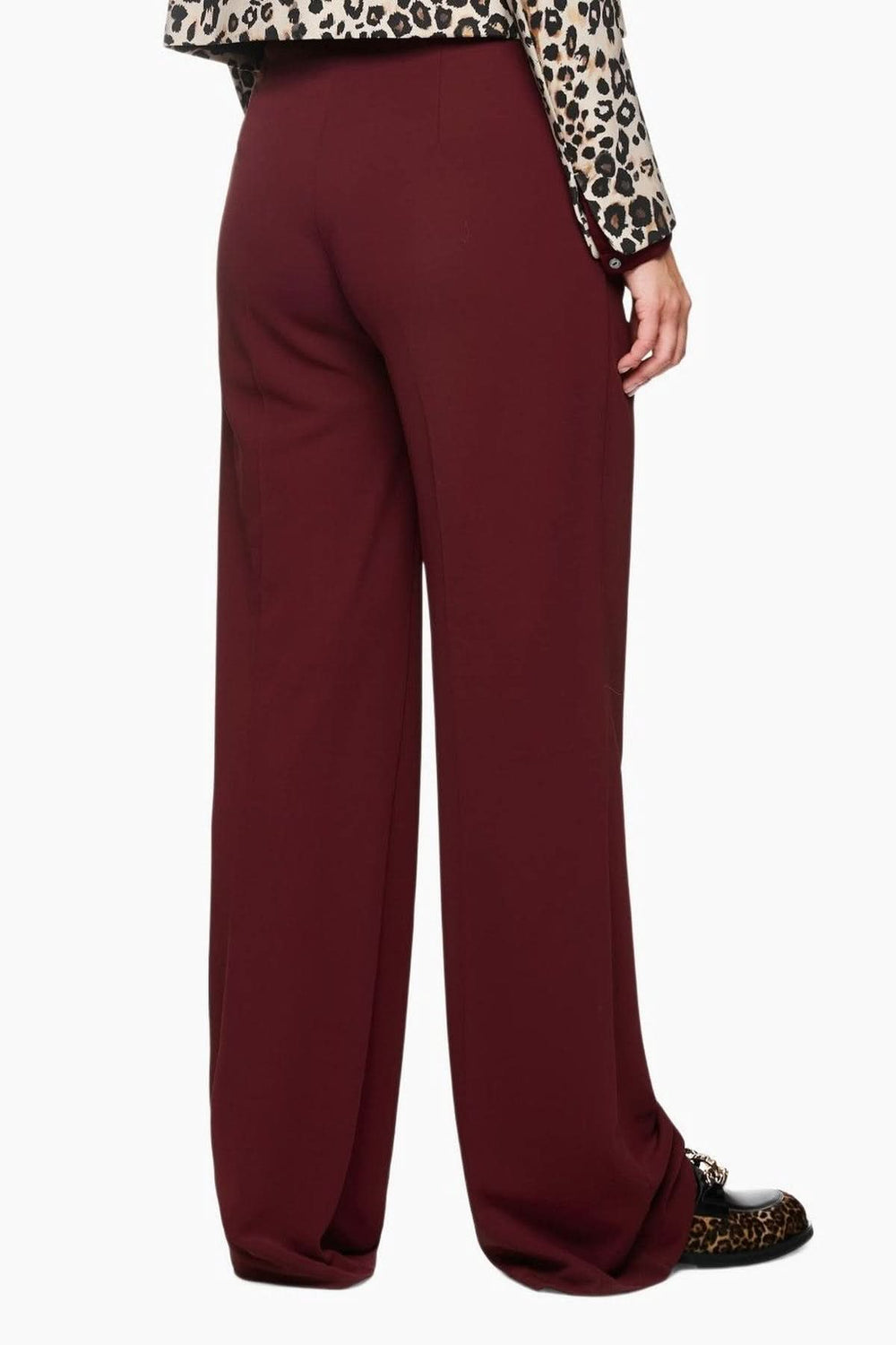 Pantalon jambes larges en tissu fluide bordeaux, coupe élégante avec taille haute et plis marqués, porté avec une chemise imprimée.
