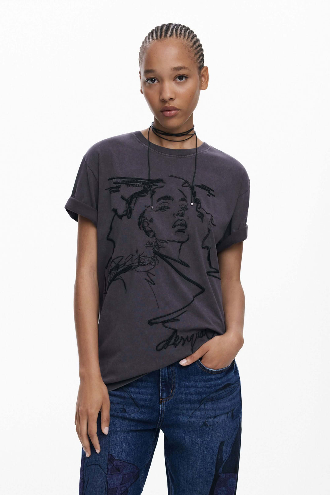 T-shirt à manches courtes avec imprimé artistique sur fond gris, porté avec un look décontracté.