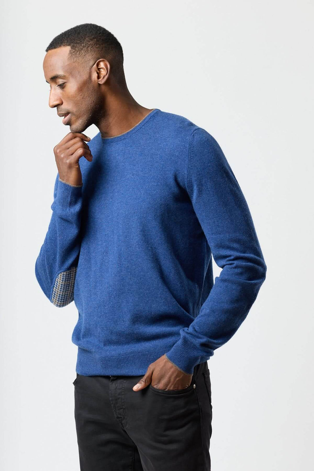 Homme portant un chandail en laine vierge et cachemire bleu avec coudières à motif pied-de-poule, style élégant et confortable.