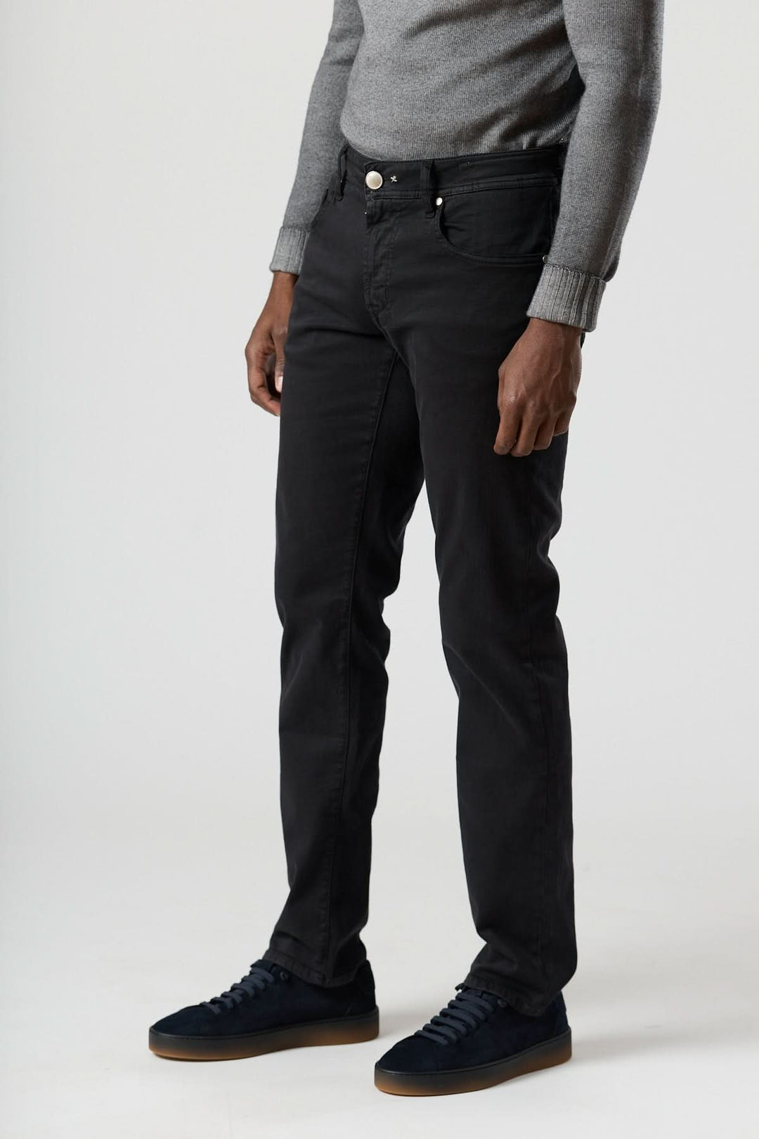 Jean 5 poches stretch coupe moderne noir pour homme, montrant une coupe fuselée avec des rivets discrets, porté avec un pull gris.