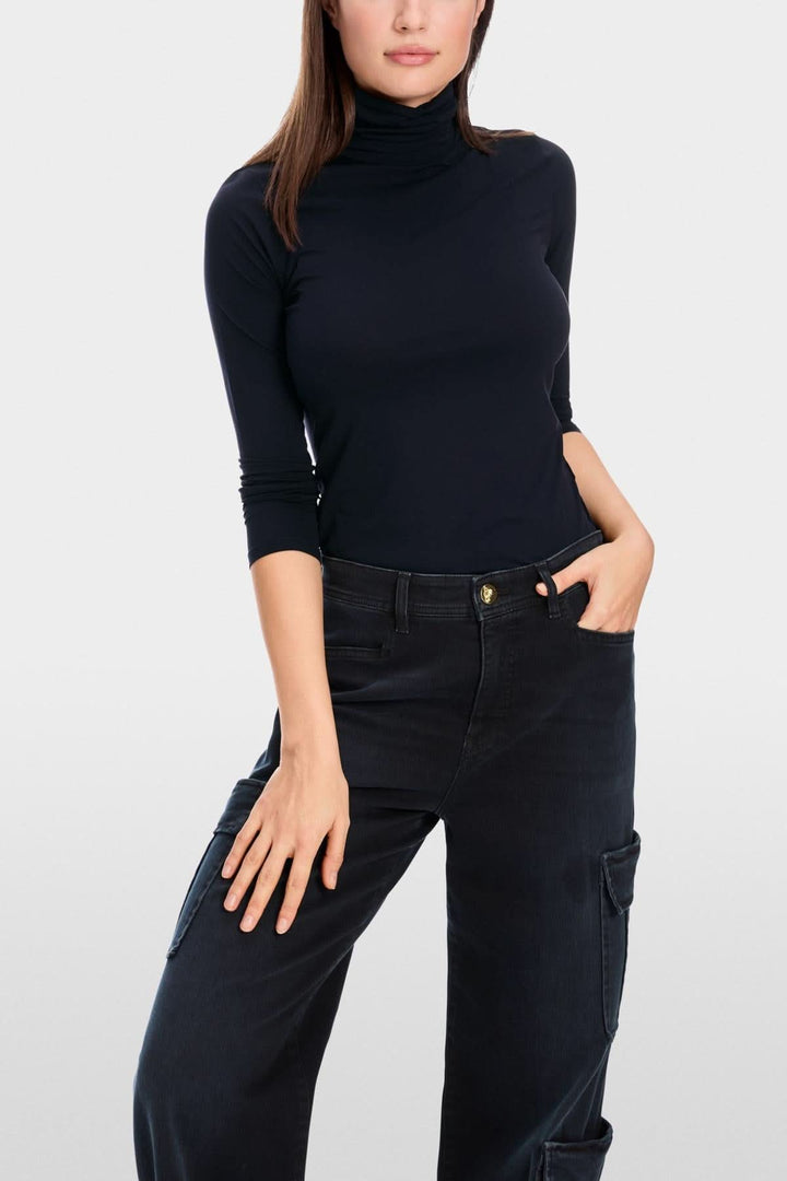 Femme portant un chandail col roulé mince noir, confortable et élégant avec un jean noir.