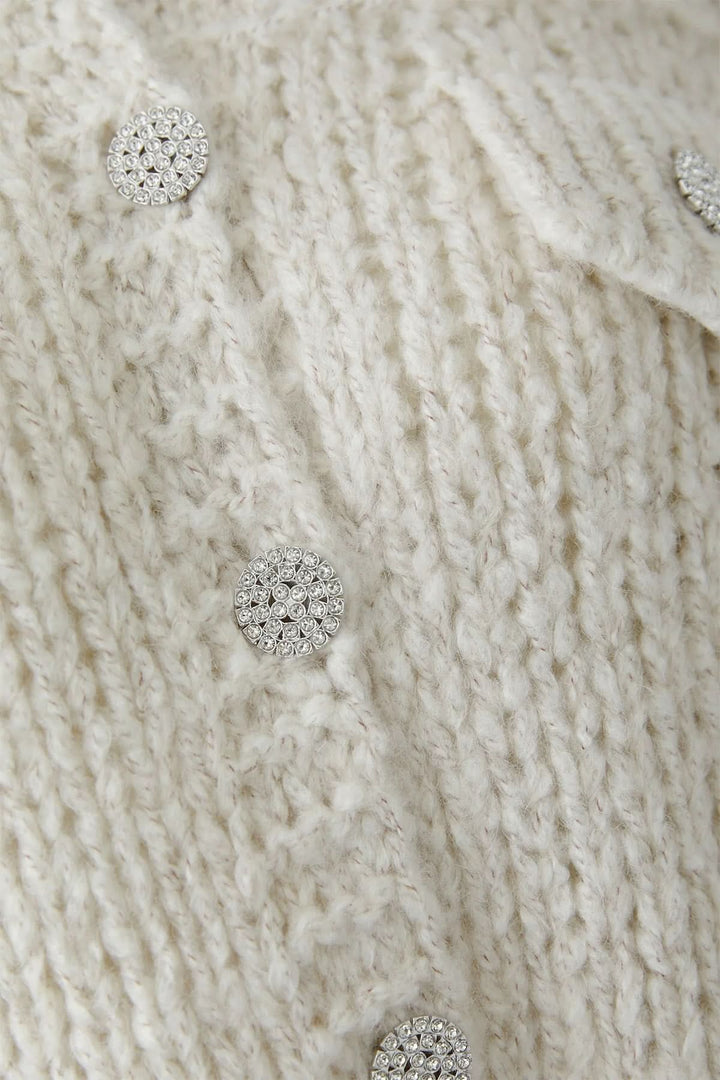 Veste en tricot épais à boutons bijoux avec détails de maille texturée et boutons scintillants décoratifs.