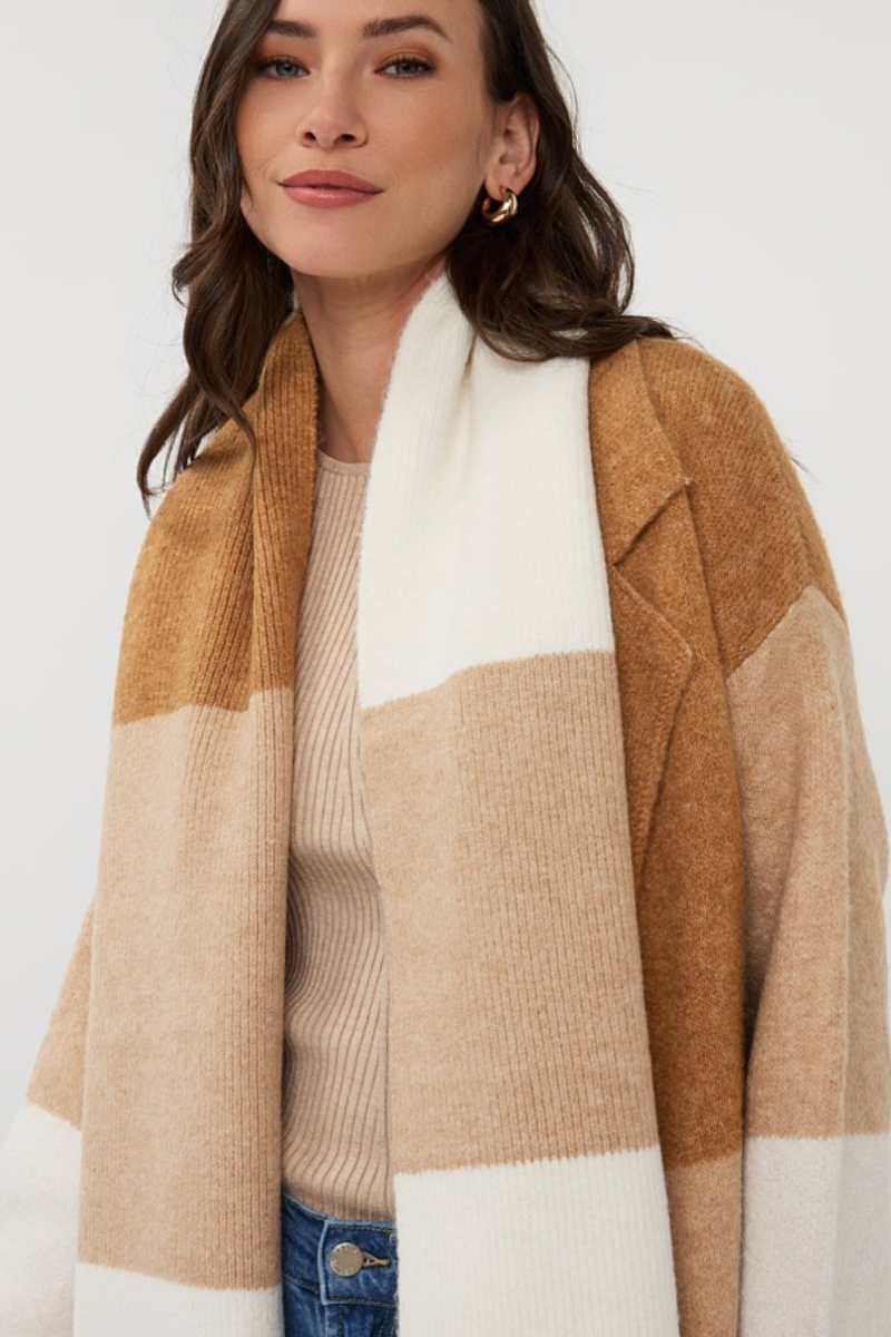 Foulard larges à rayures graphiques en ton beige, porté avec une tenue décontractée, pour un look moderne et cocooning.