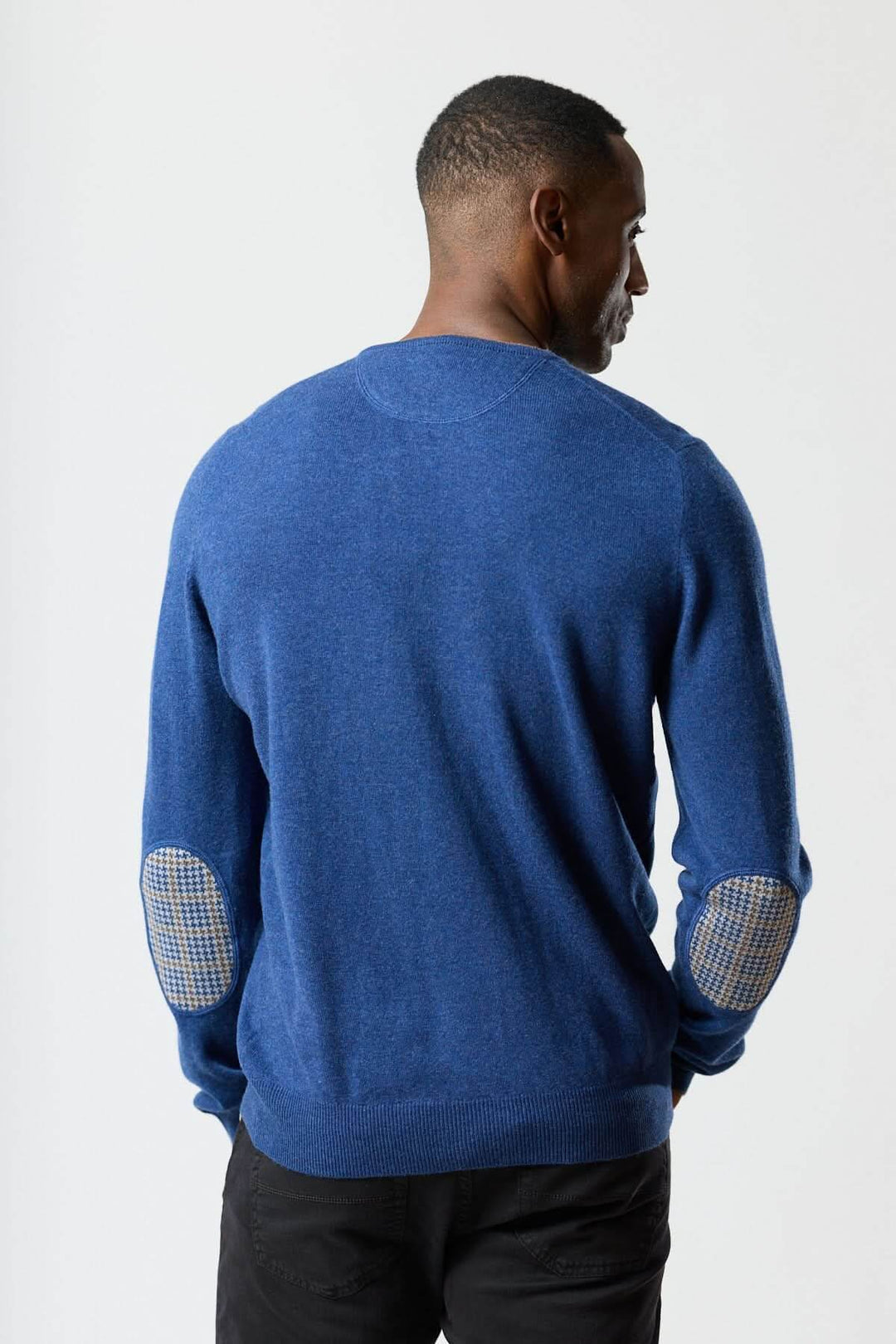 Homme portant un chandail en laine vierge et cachemire bleu avec coudières pied-de-poule, élégance italienne, douceur exceptionnelle.