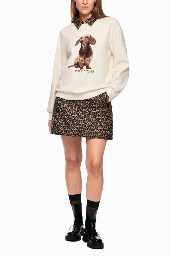 Femme portant un coton ouaté imprimé chien "Stay Pawsitive" avec jupe léopard, style tendance. Mots clés: Coton ouaté imprimé chien.