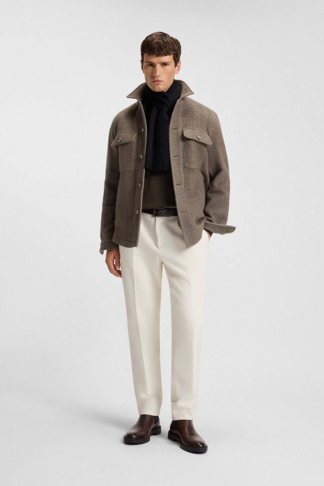 Homme portant un foulard de laine vierge Boss noir, chic et discret, avec une tenue hivernale élégante, parfait pour l'hiver.