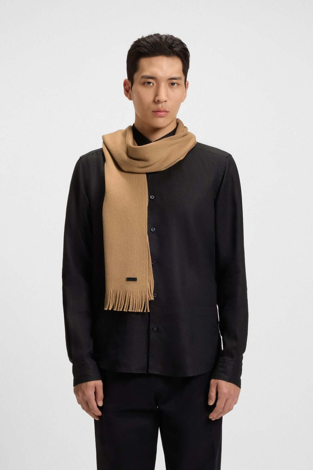Homme portant un Foulard de laine vierge Boss beige, élégance hivernale avec étiquette logo discrète.