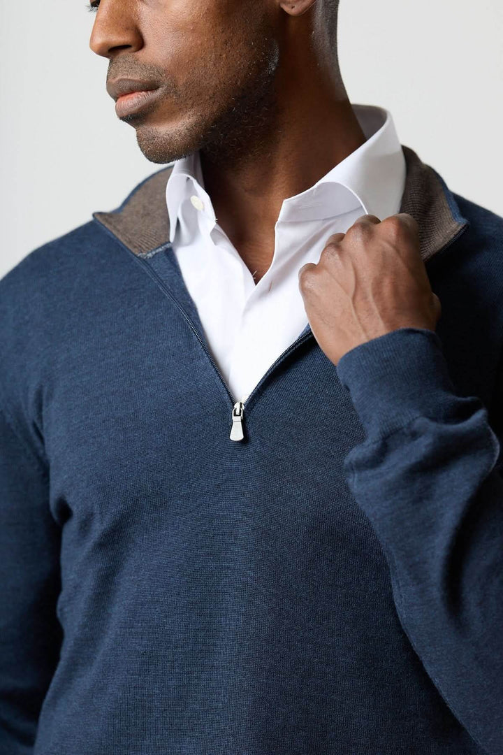 Homme portant un chandail à demi-zip en laine mérinos bleu avec chemise blanche, élégance moderne et polyvalente.