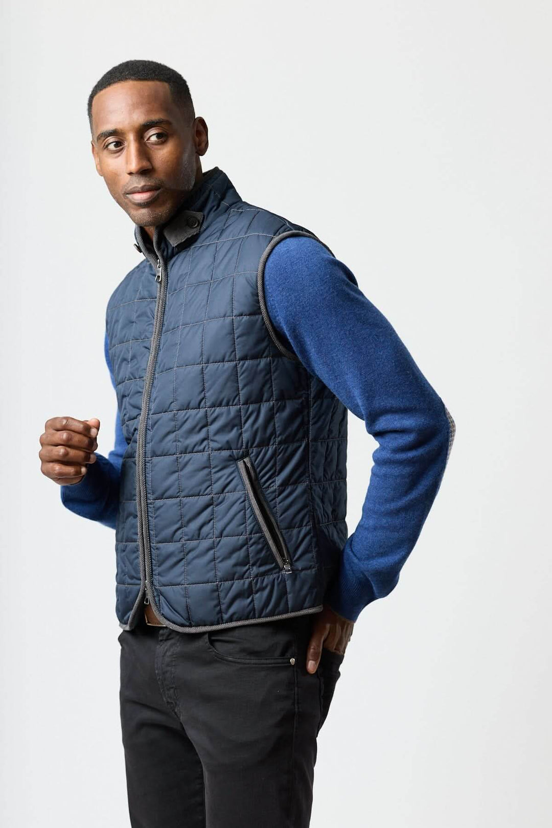Veste sans manches matelassée avec détails en velours côtelé portée sur un homme élégant, ajoutant style et confort sophistiqué.