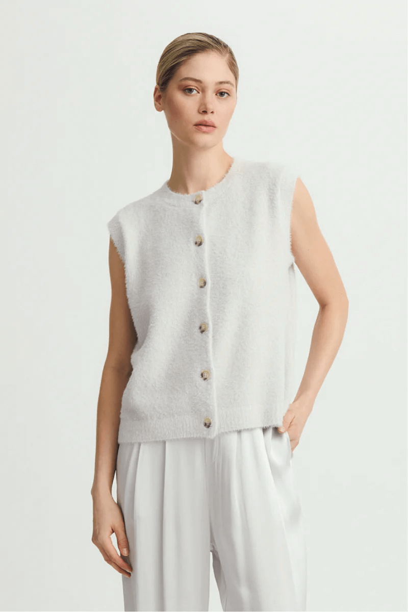 Veste sans manche Alexe, femme portant une veste moderne en maille douce avec fermeture à boutons, coupe décontractée, élégante et polyvalente.