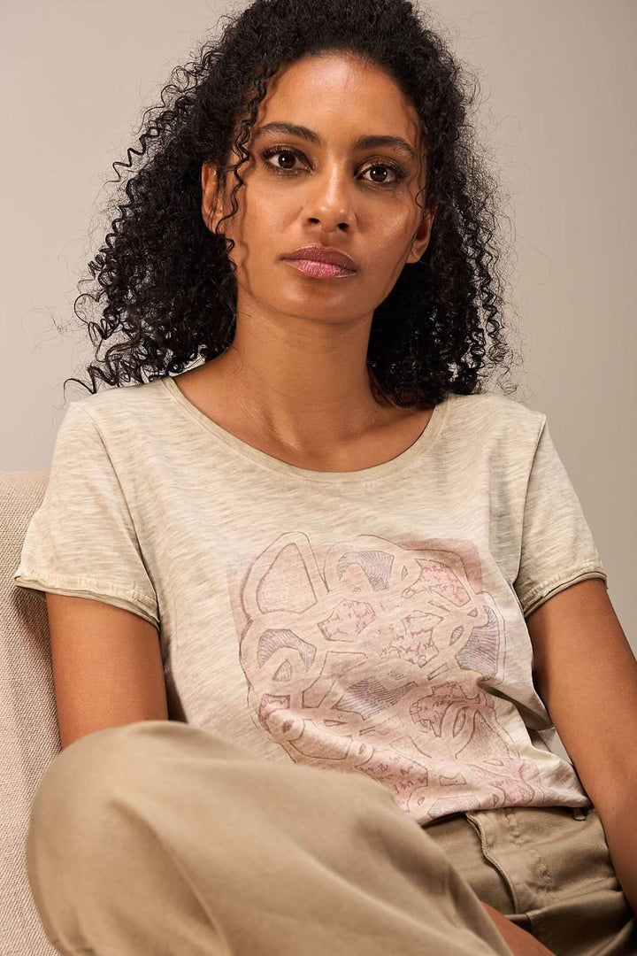 Femme portant un t-shirt à manches courtes avec un imprimé artistique sur le devant, style décontracté.