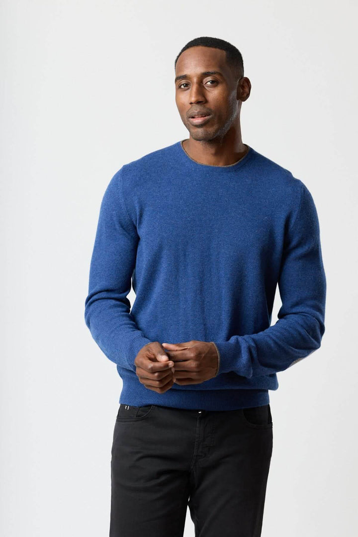 Homme portant un chandail en laine vierge et cachemire bleu, design Gran Sasso, avec coudières pied-de-poule, élégant et confortable.