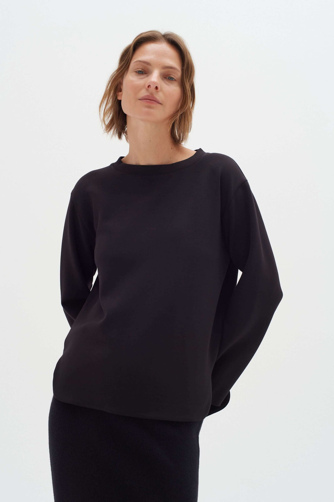 Chandail Gincent noir à manches longues, col bateau, silhouette minimaliste pour un style élégant et confortable.