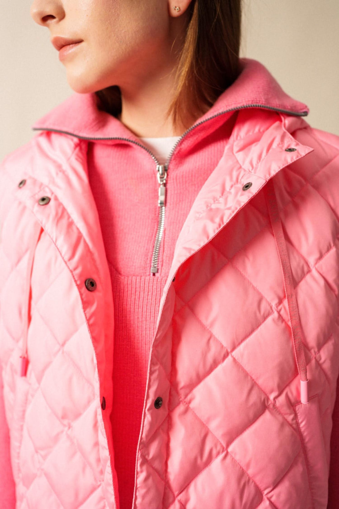 Doudoune sans manche STE JODIE, matelassée rose, col montant et capuche intégrée, portée sur un pull en maille.