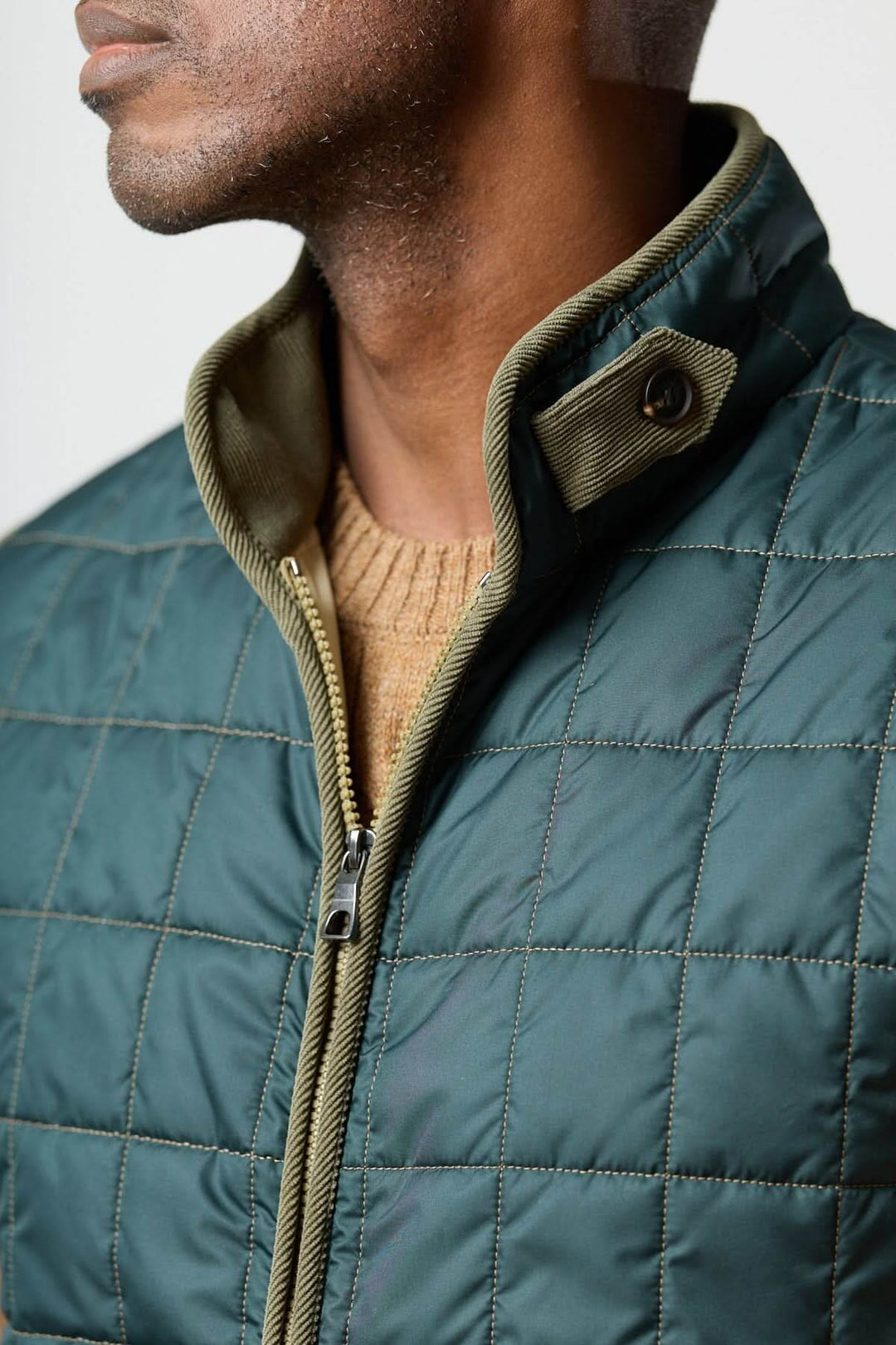 Veste sans manches matelassée avec détails en velours côtelé, vue de près sur le col et le tissu, élégante et pratique.