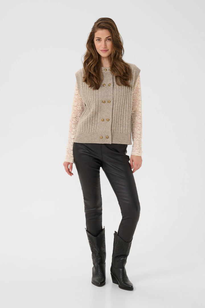 Femme portant une Veste Eroka sans manches en tricot à boutons dorés avec texture côtelée, idéale pour superposer dans un style décontracté.