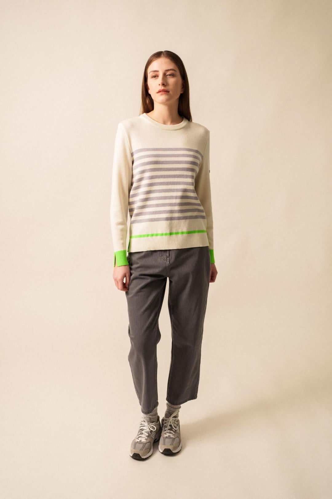 Chandail Evian rayé avec finitions fluo, porté avec pantalon gris et baskets, style moderne et décontracté.