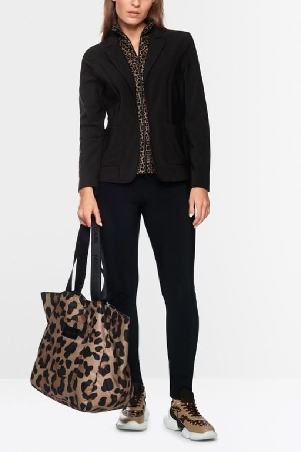 Femme portant une veste avec supperposition et haut zippé léopard, complété par un sac léopard, tenue à la fois décontractée et professionnelle.