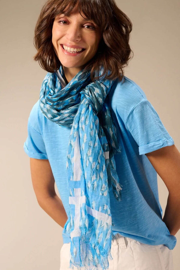 Foulard léger à imprimé bleu porté par une femme souriante, accessoire mode élégant et polyvalent.