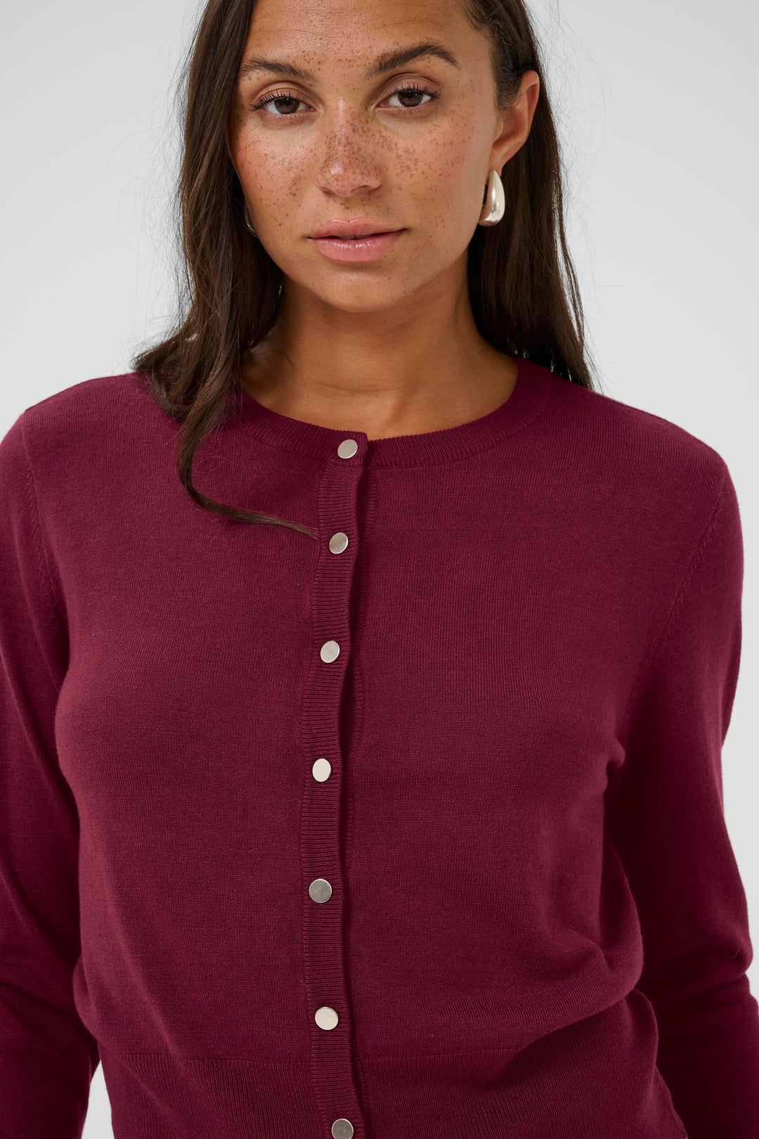 Cardigan Lizza classique à encolure ronde et boutons porté par un mannequin, coupe ajustée, boutons métallisés, couleur bordeaux.