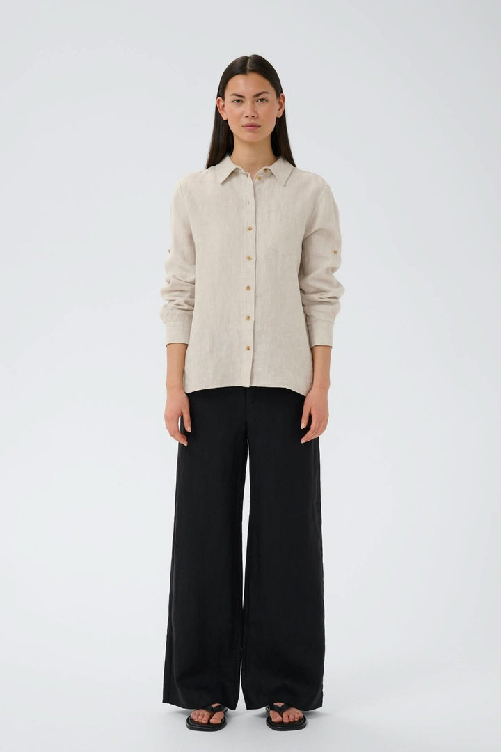 Modèle portant le Pantalon de lin Solina avec taille haute et jambes larges, style décontracté avec chemise beige.