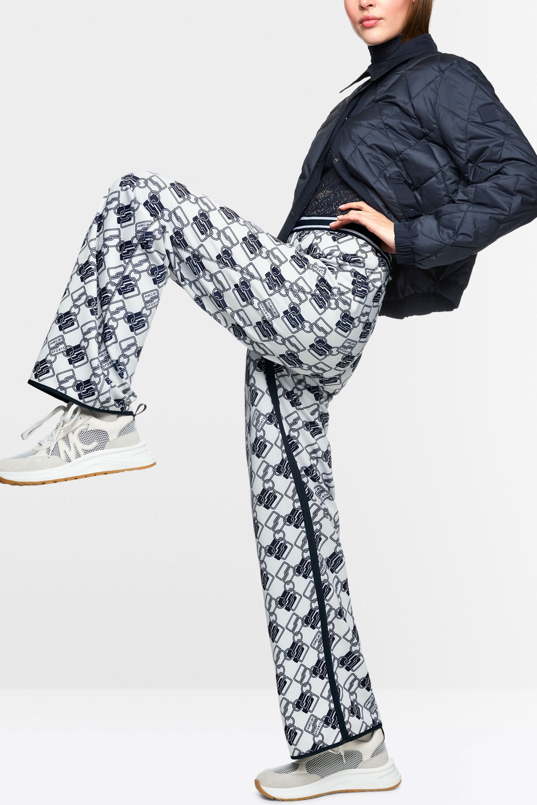 Femme portant un pantalon de jogging réversible Washington avec motifs entrelacés et bandes latérales, style sport-chic.