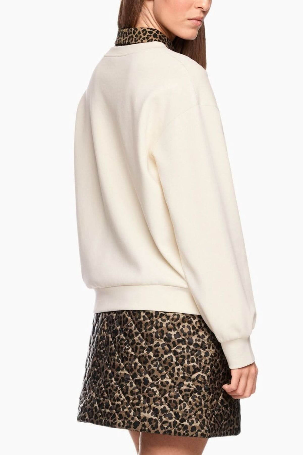 Femme portant un coton ouaté imprimé chien avec jupe léopard, vue de dos, style casual et moderne.