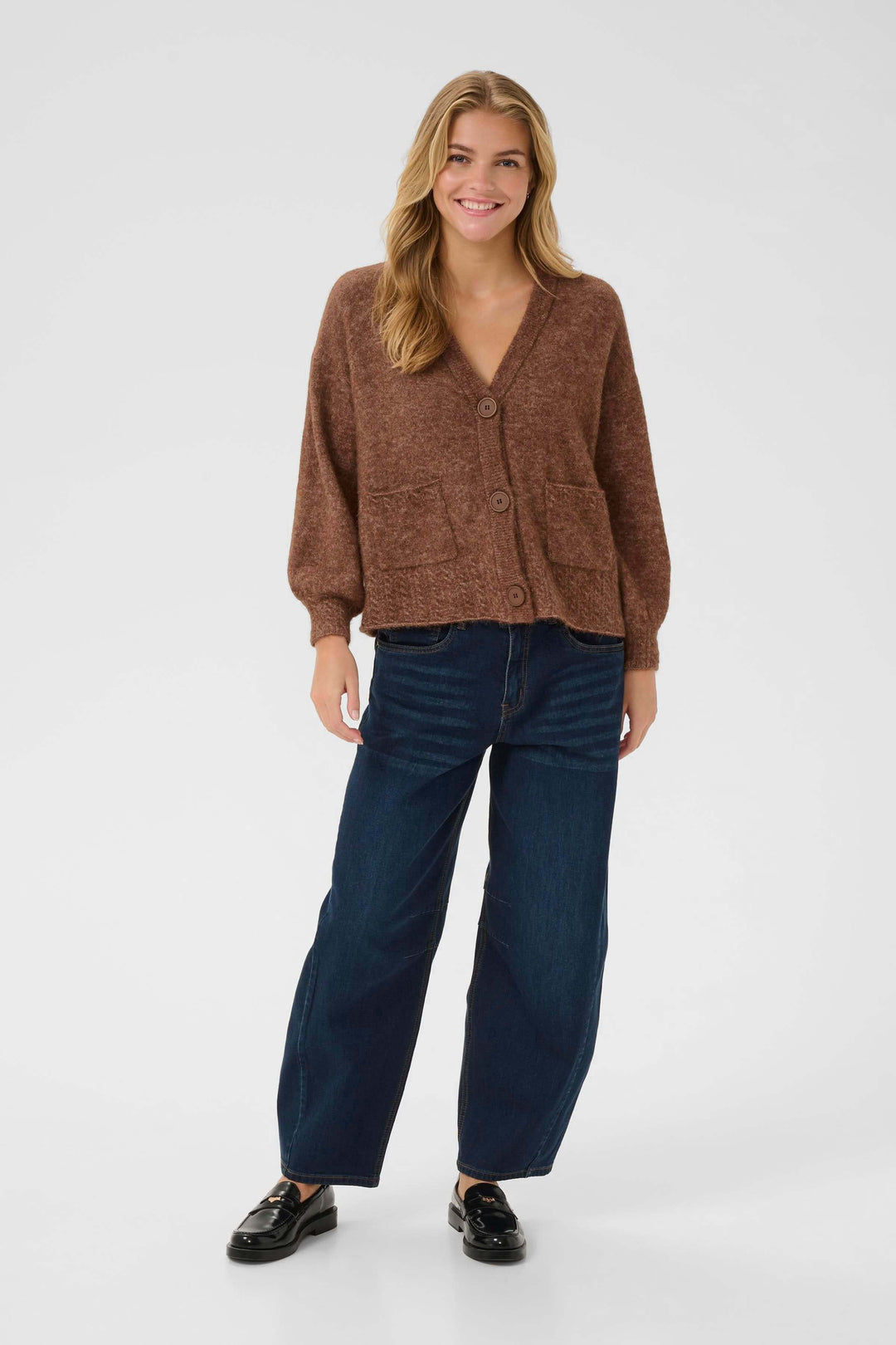 Femme portant un Cardigan Blues en tricot doux à boutons apparents avec poches, ajoutant confort et style à sa tenue décontractée.