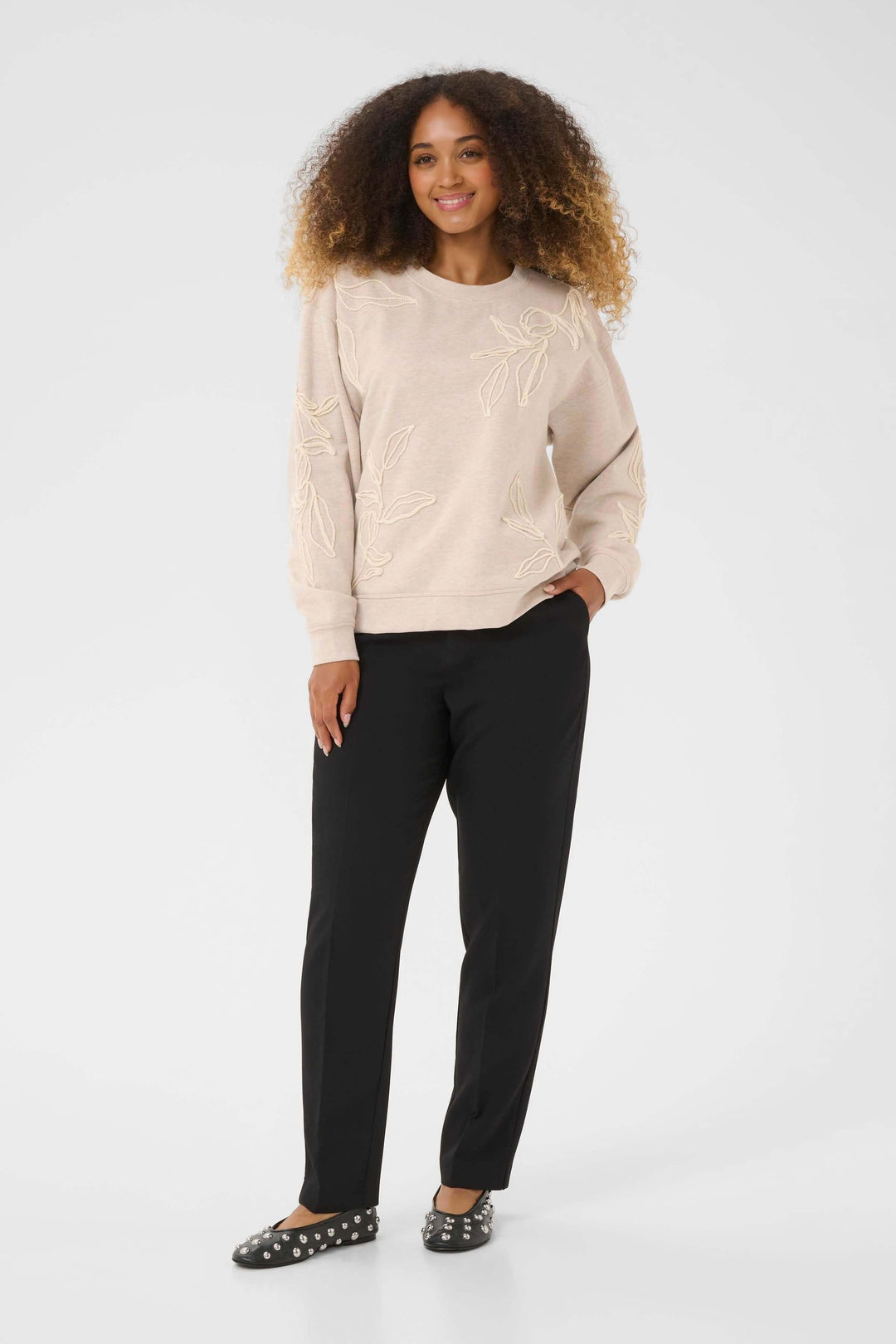 Femme portant le Chandail Lovisa en coton ouaté à broderies ton sur ton pour un look décontracté et élégant, avec motif floral délicat.