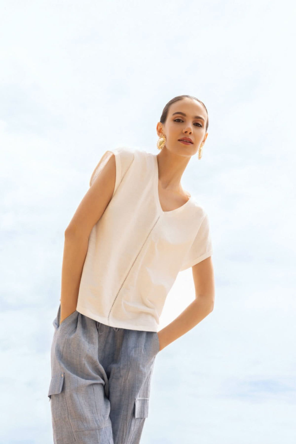 Femme portant un haut fluide col en V blanc avec pantalon décontracté, style moderne et élégant.