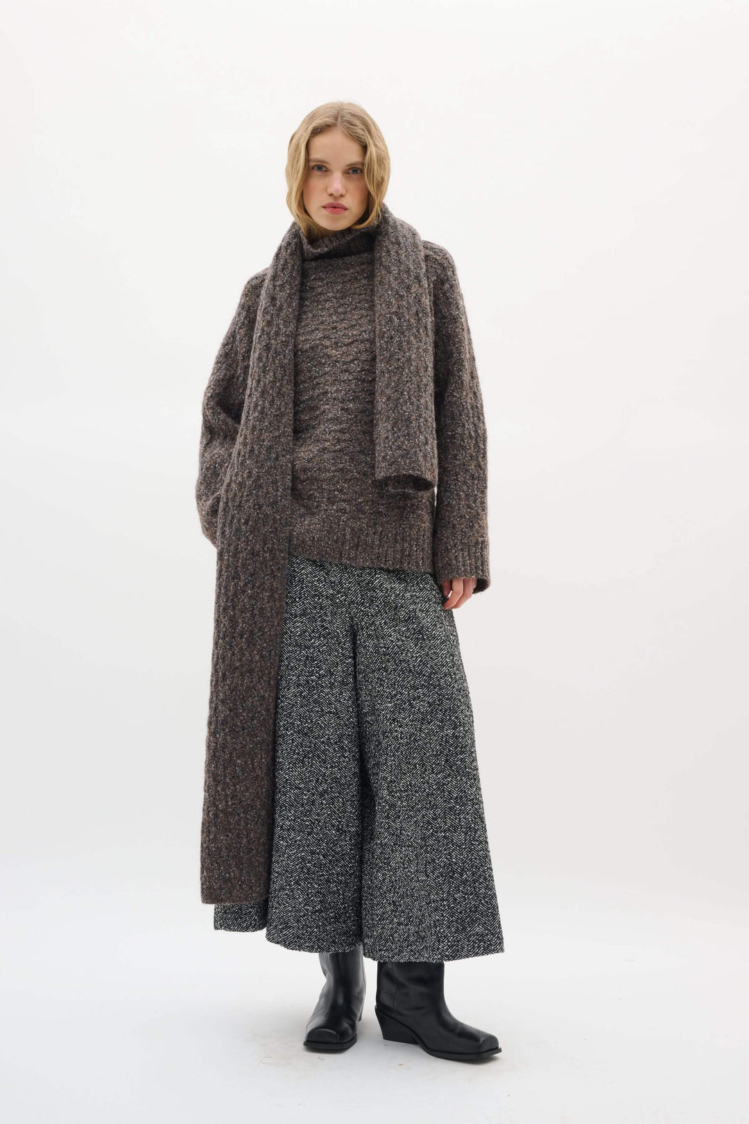 Foulard Graia en maille texturée, long et épais, porté sur un manteau, offrant chaleur et style moderne pour la saison froide.