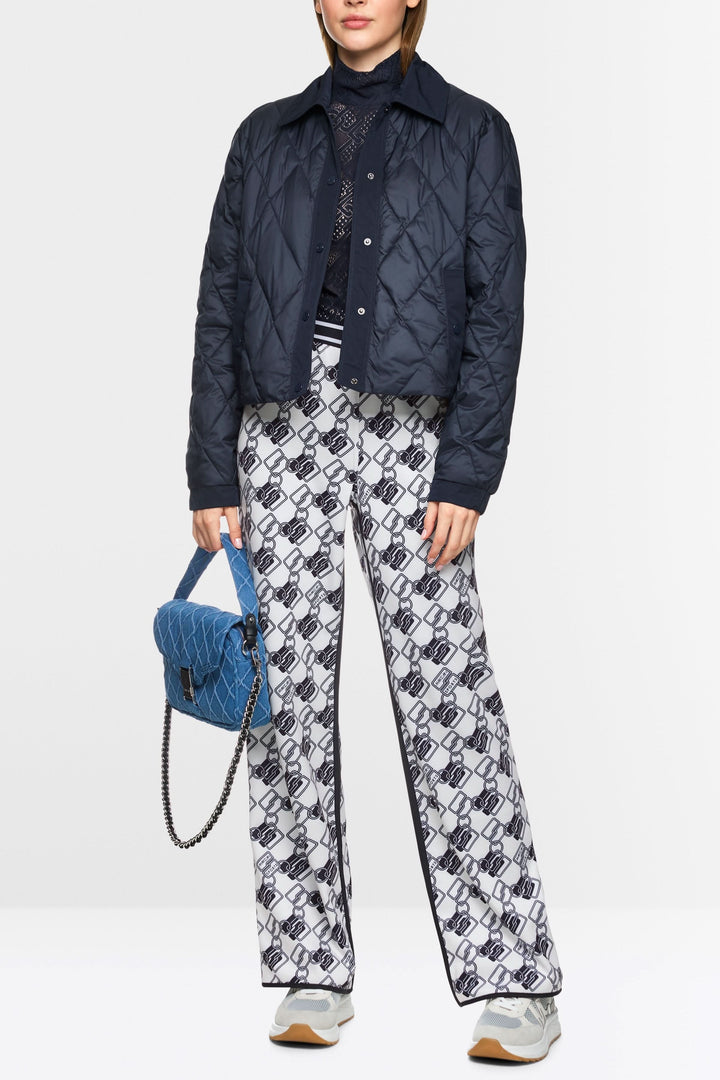 Femme portant un pantalon de jogging réversible Washington avec un haut matelassé et un sac bleu, look sport-chic.