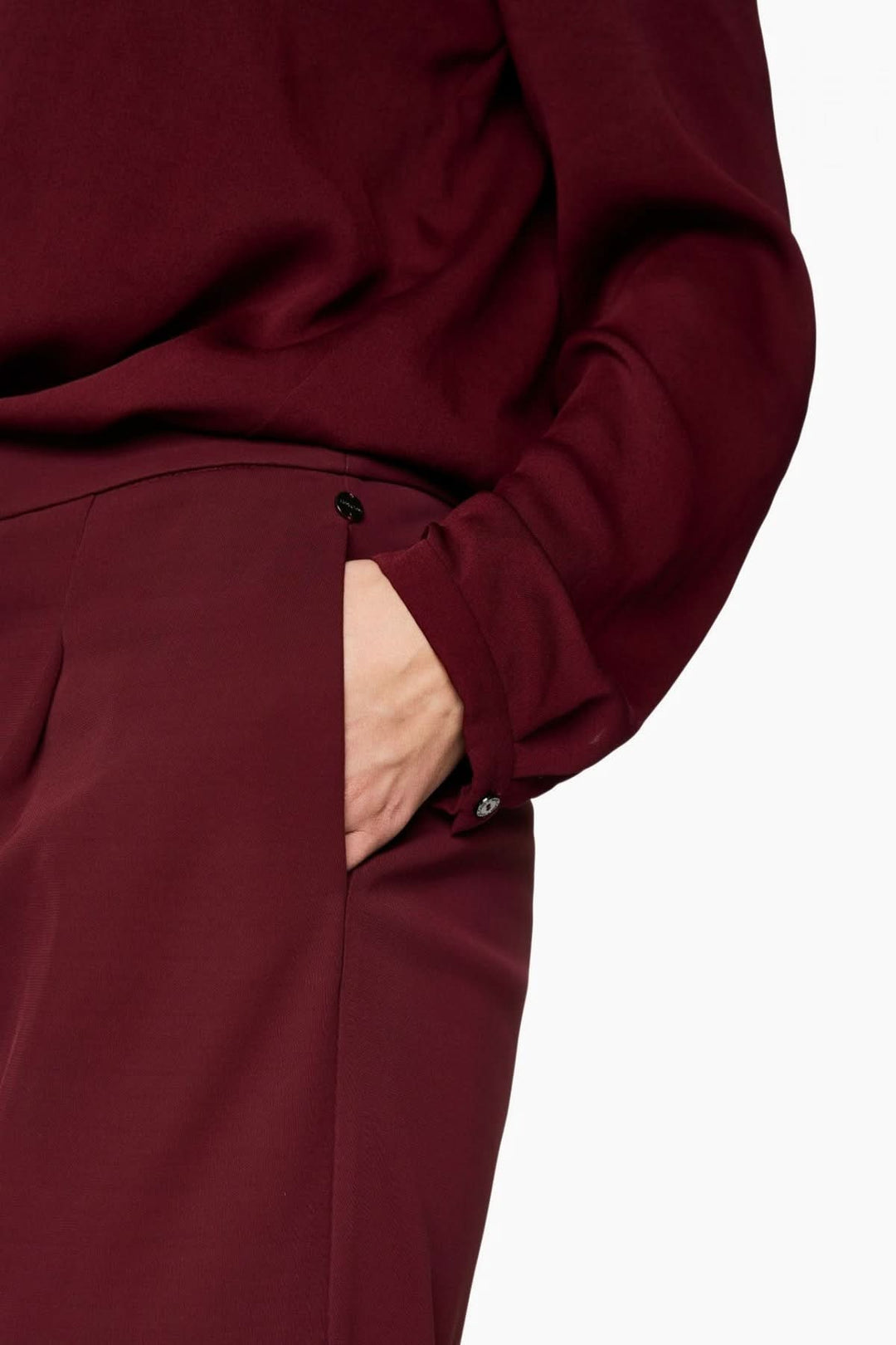 Pantalon jambes larges bordeaux élégant avec taille haute et plis marqués, en matière fluide, pour un look chic et confortable.