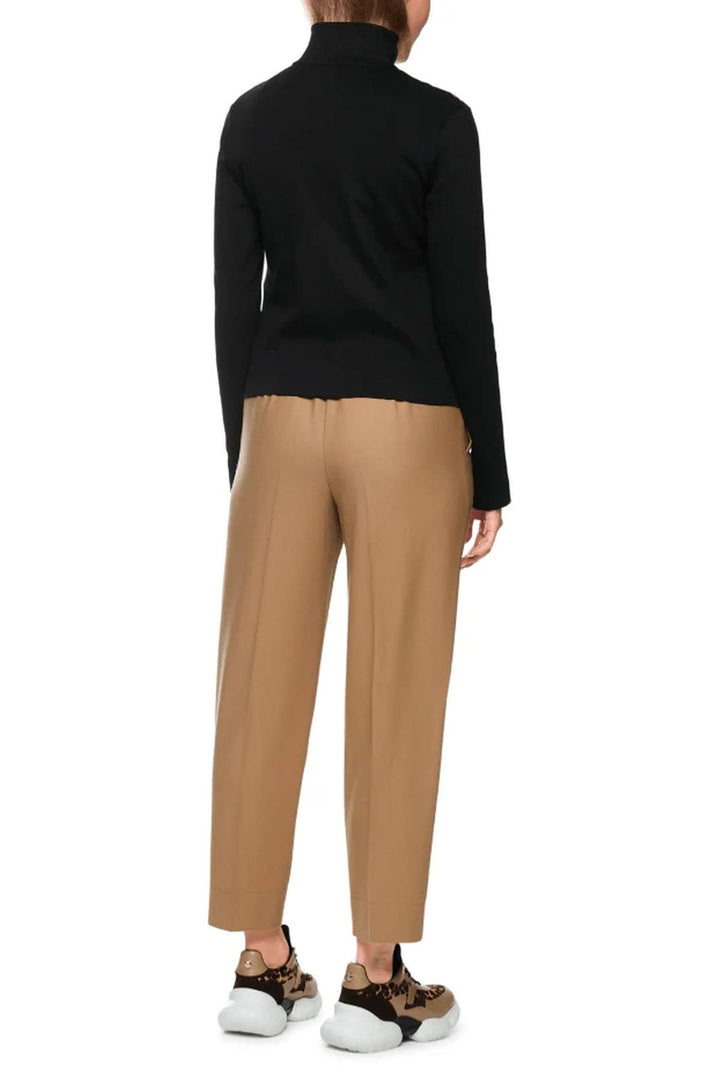 Dos d'une tenue avec pantalon beige et pull noir, mettant en valeur le design moderne et contrasté. Veste avec manche non visible ici.