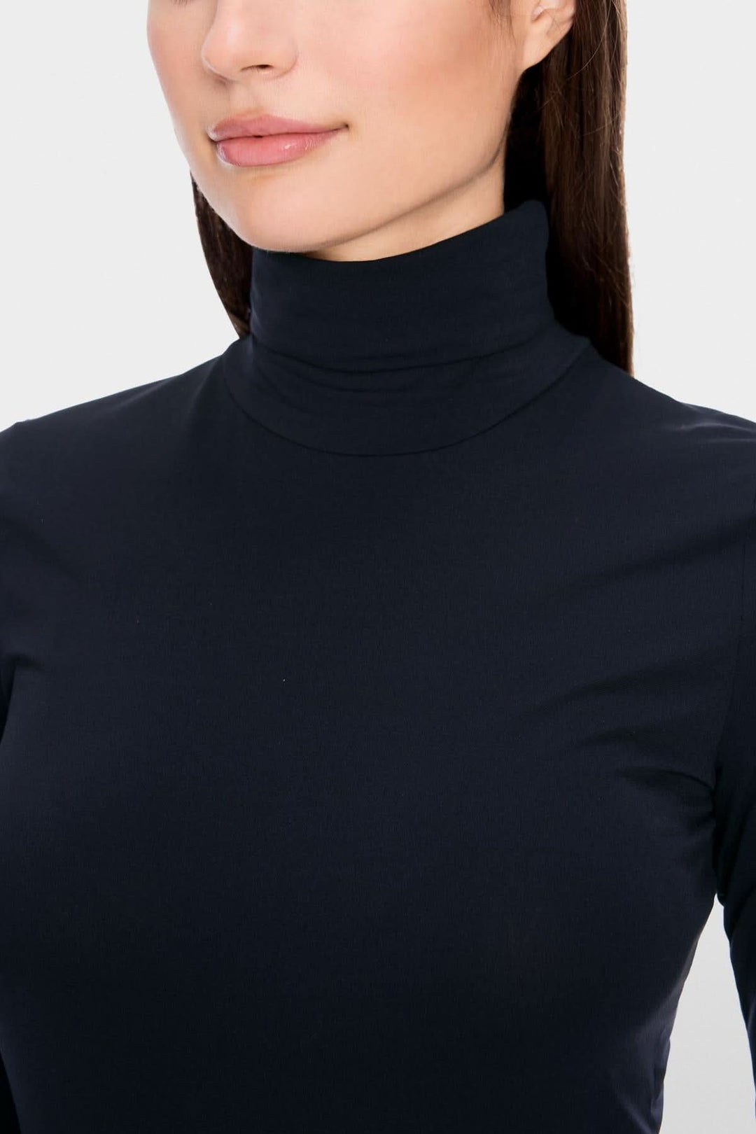 Femme portant un col roulé mince, en tissu extensible, coupe légèrement cintrée pour un look élégant et confortable.