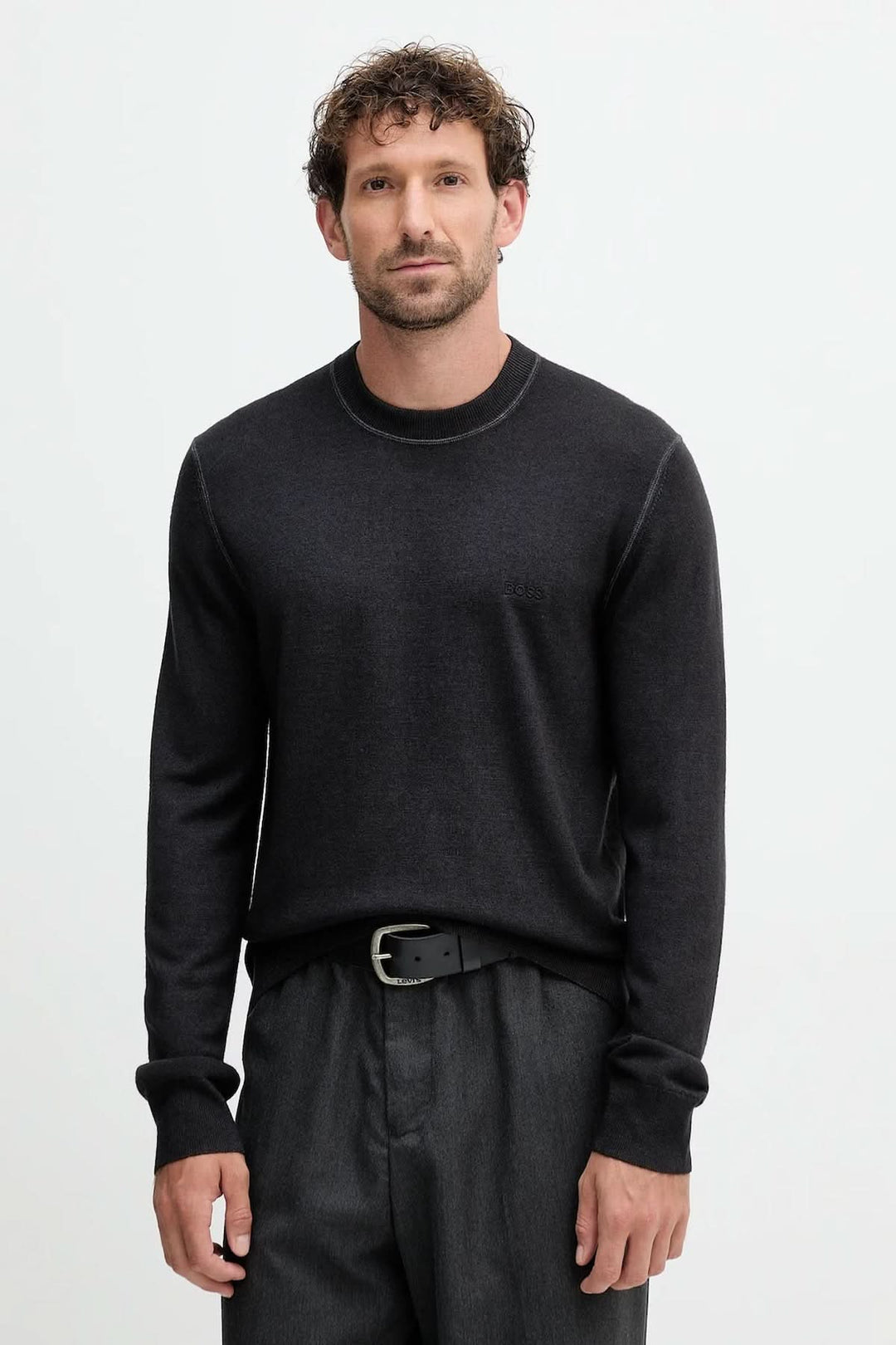 Homme portant un chandail en laine vierge à col rond de BOSS Orange avec manches longues et finitions côtelées, style décontracté.