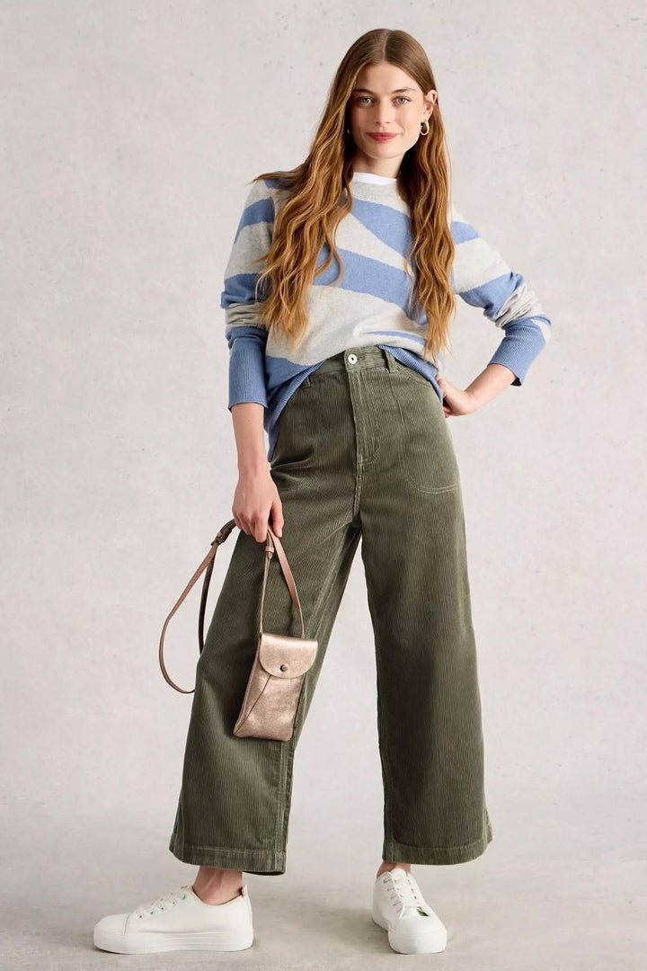 Pantalon Tia en velours côtelé avec coupe évasée, taille haute, porté avec un chandail rayé et des baskets blanches.