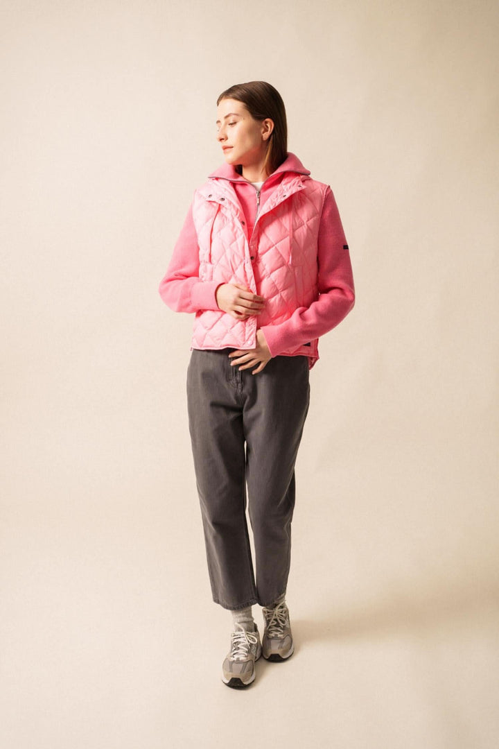 Femme portant une doudoune sans manche STE JODIE rose, style sportif, avec capuche intégrée et looks urbains.