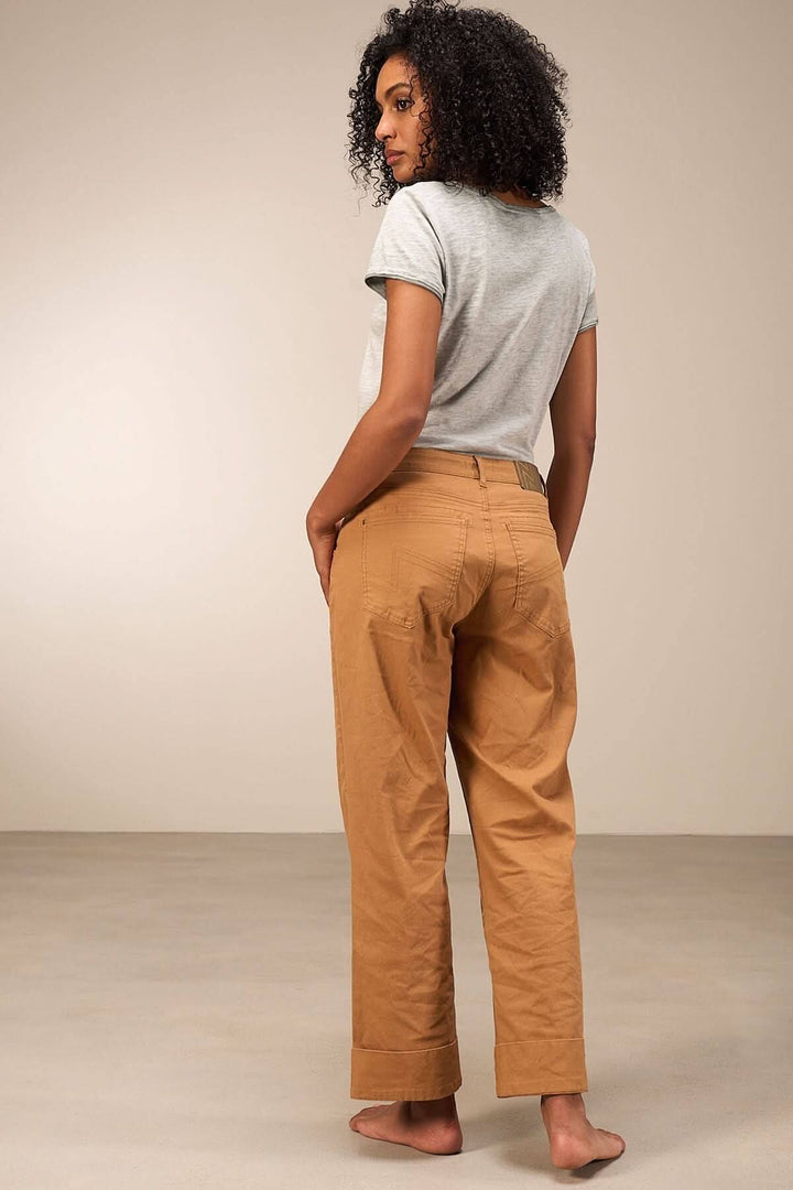 Femme de dos portant un t-shirt gris et un pantalon beige, affichant un look décontracté et moderne.