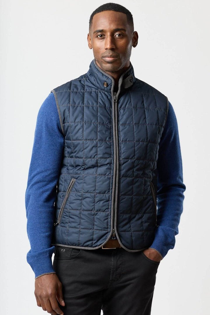 Homme portant une veste sans manches matelassée avec détails en velours côtelé, tenue élégante et pratique.