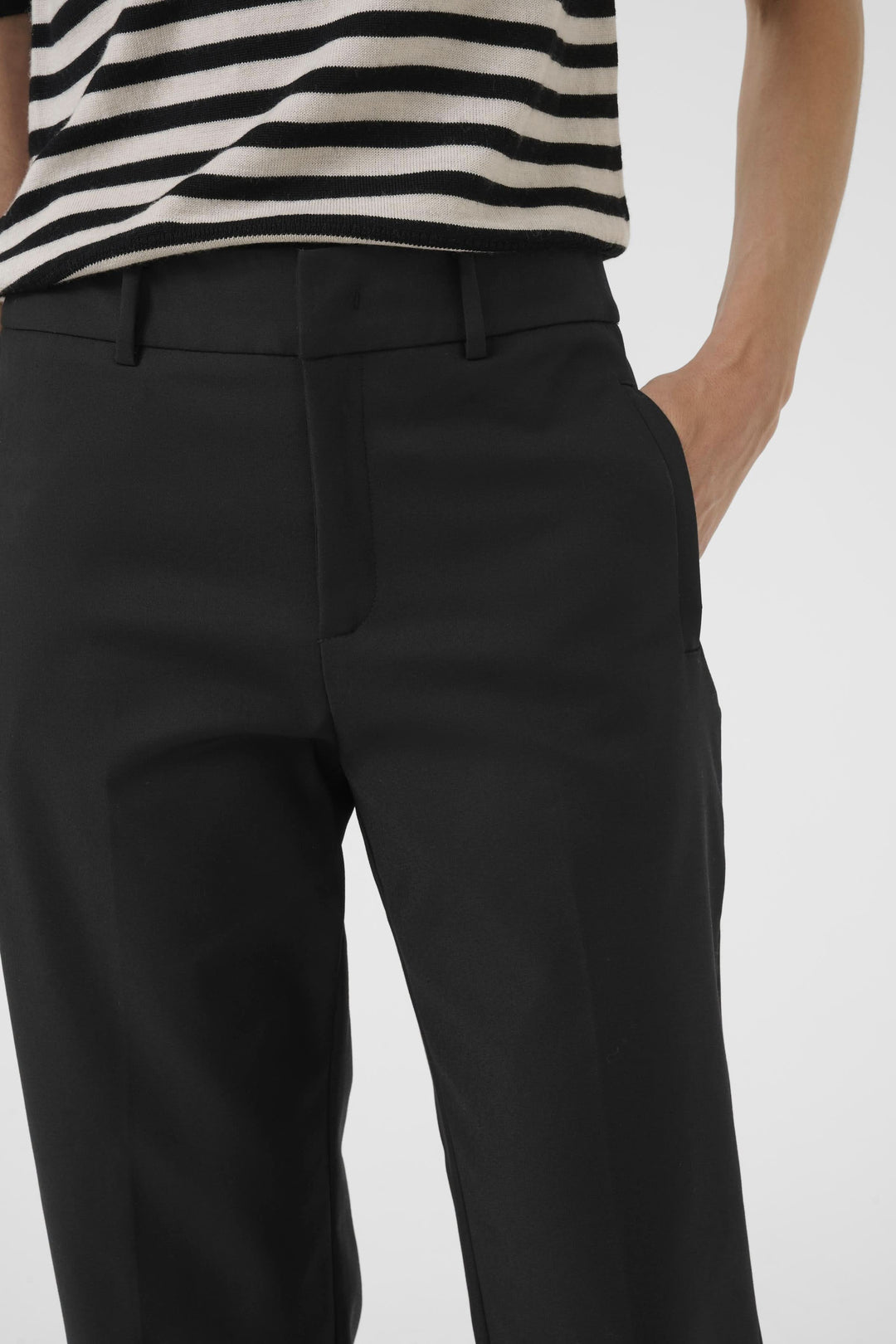 Pantalon Neyana classique, jambe droite, taille régulière, en tissu structuré, avec plis marqués et précise à la cheville.