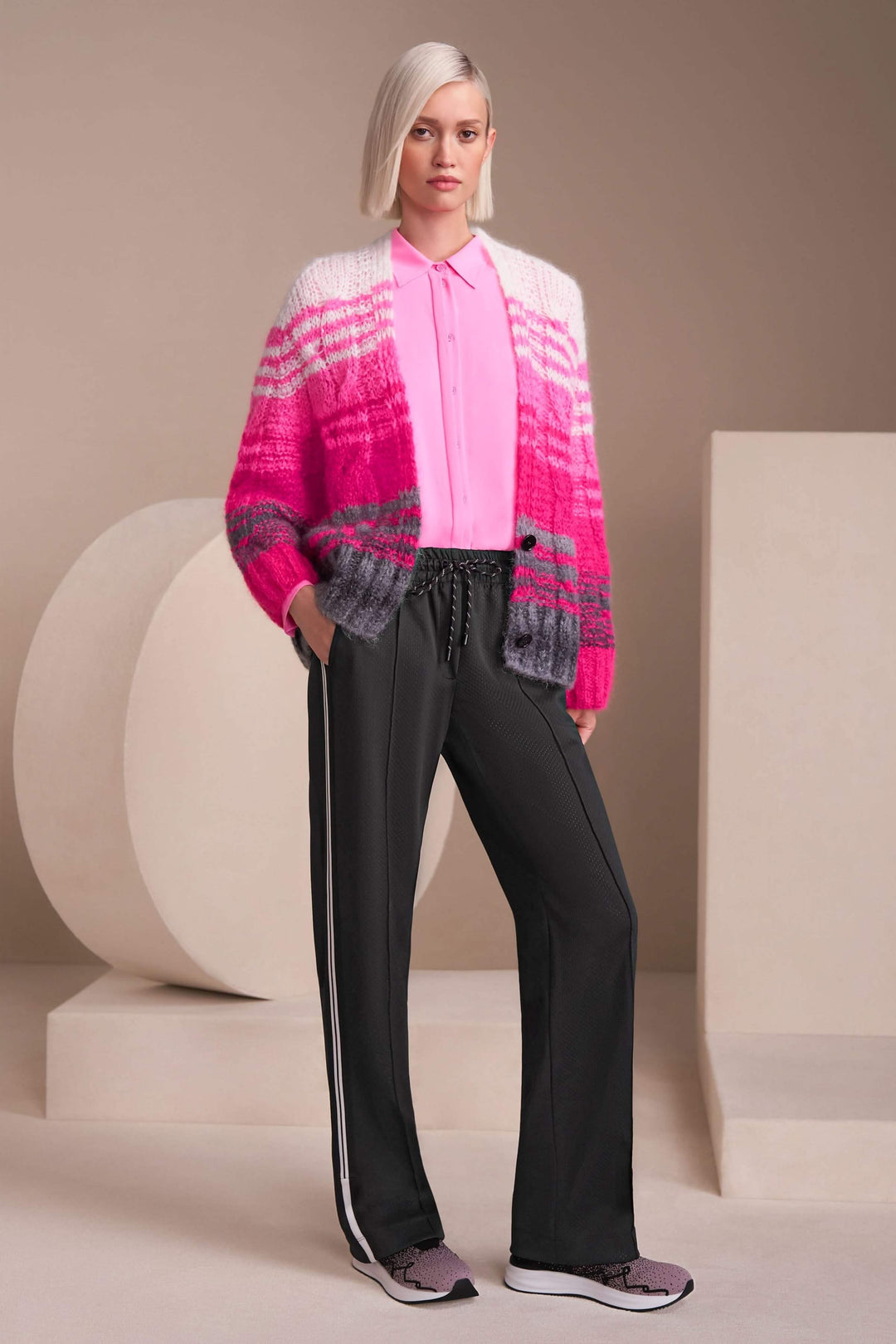 Femme portant un pantalon Washington sportwear noir avec une chemise rose et un cardigan coloré.